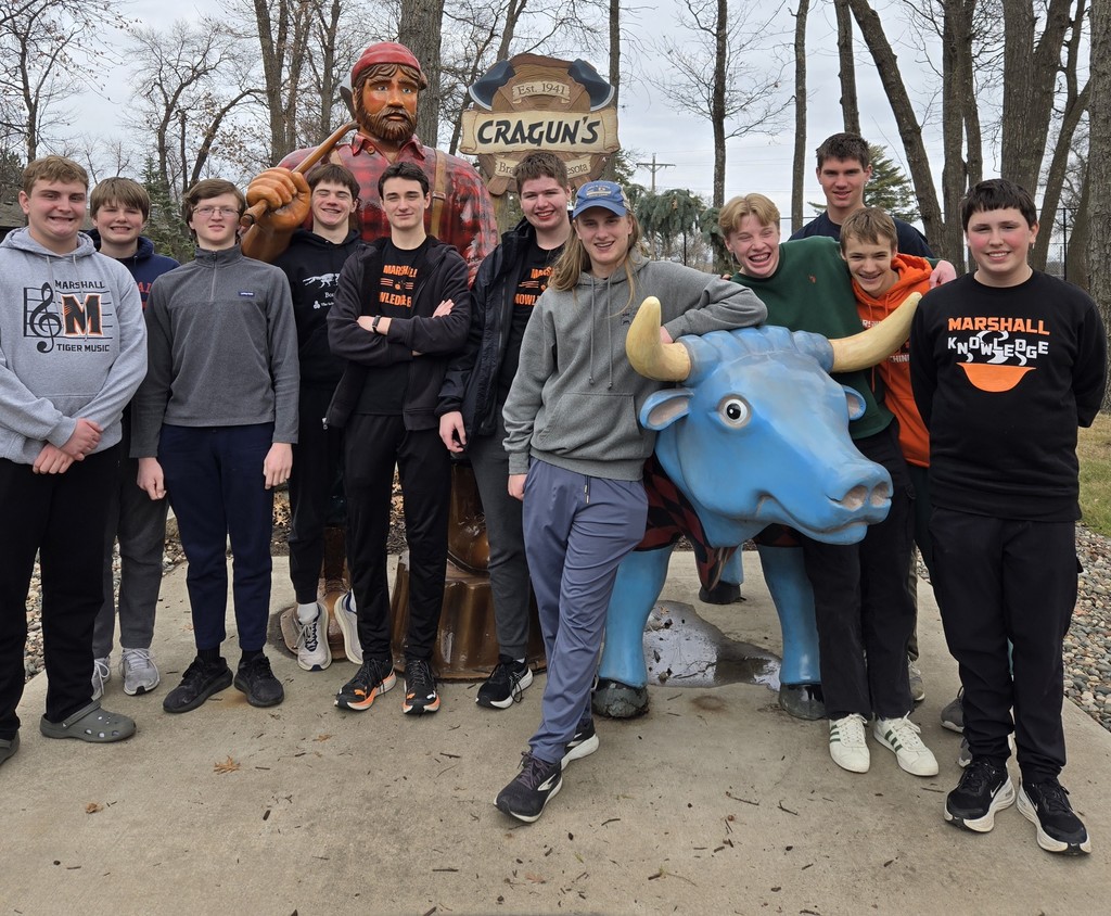 Group of young men standing either a large man statue and a blue bull statue.