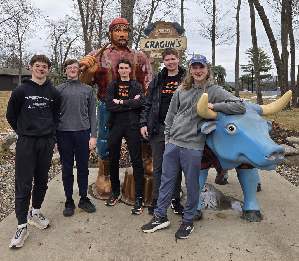 Group of young men standing either a large man statue and a blue bull statue.