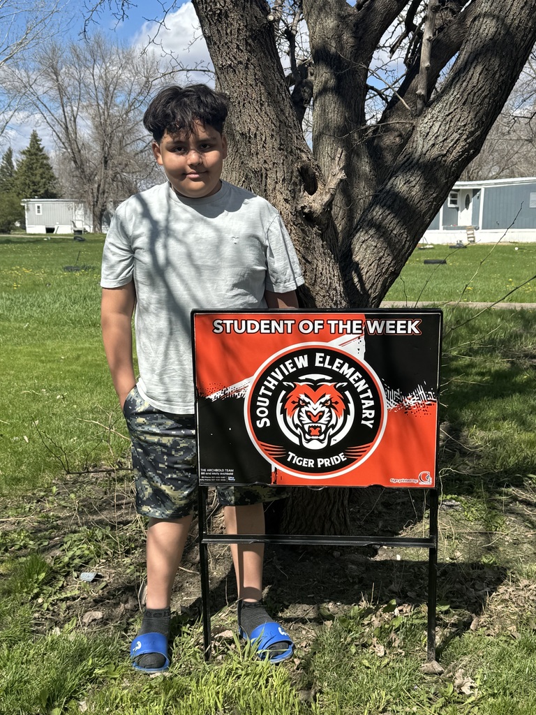 Little boy standing next to Tiger Student of the Week Sign