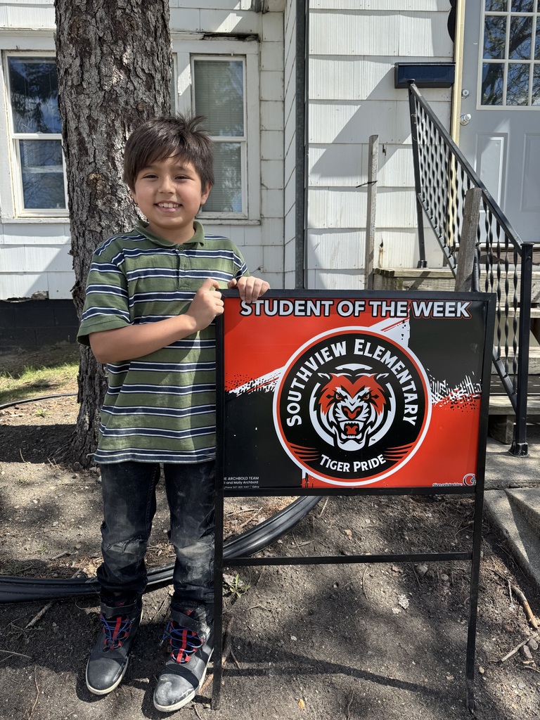 Little boy standing next to Tiger Student of the Week Sign