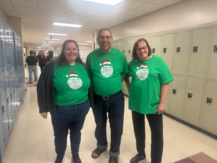 teachers wearing Santa shirts; Santa beard has “6-7” hiding in it