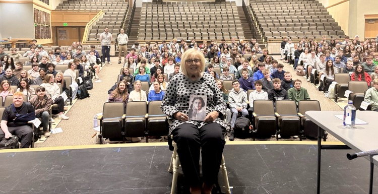 Janet on stage with students in auditorium behind her