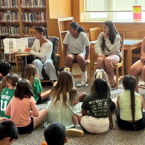older students reading books aloud to younger students