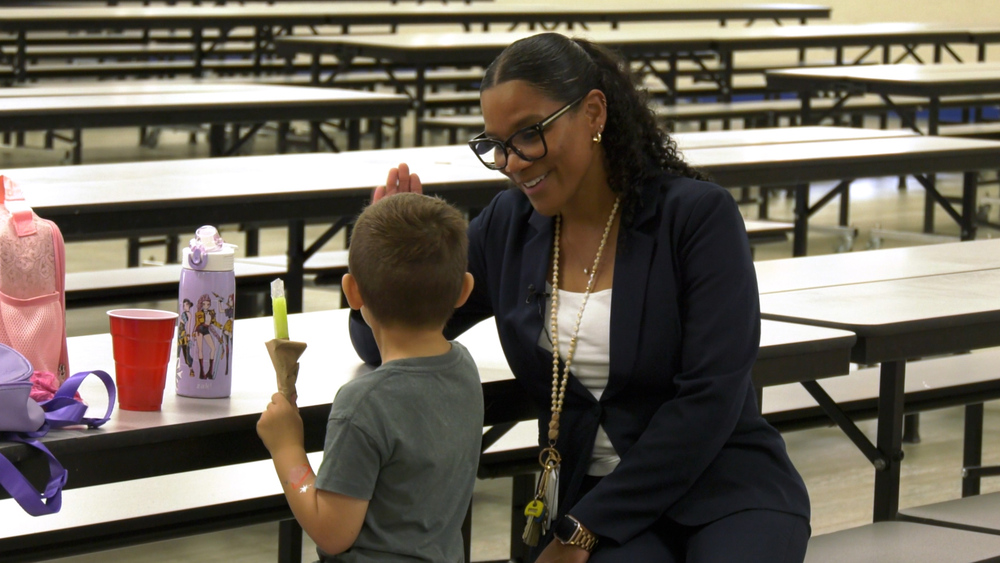 Jayde Norwood talking to a student in the cafeteria at J.D. Parker Elementary School