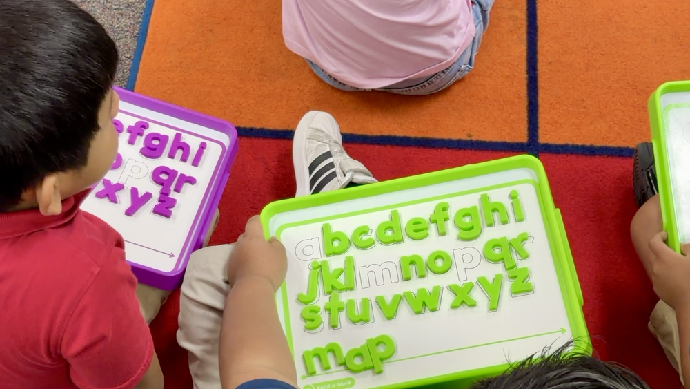 Kindergarten students spell words during class on their magnet letter  boards