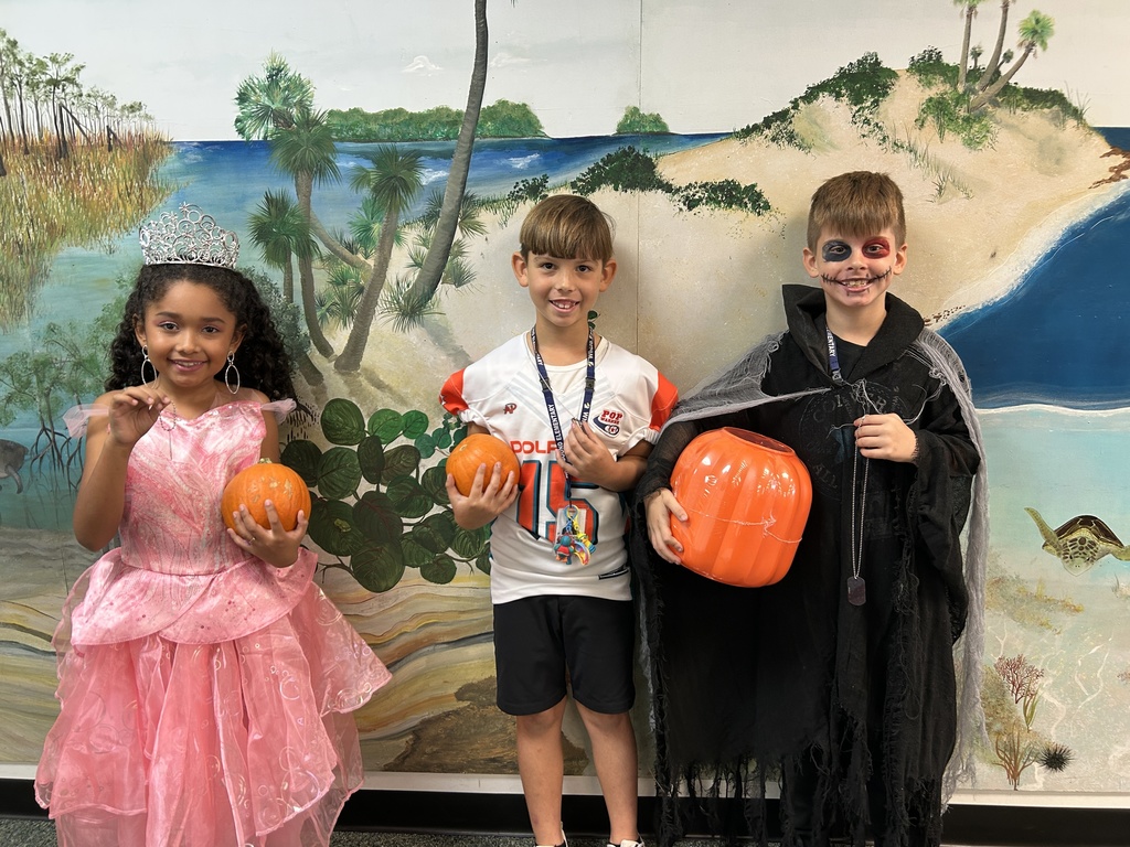 Three students dressed in costume winning pumpkins for reading.