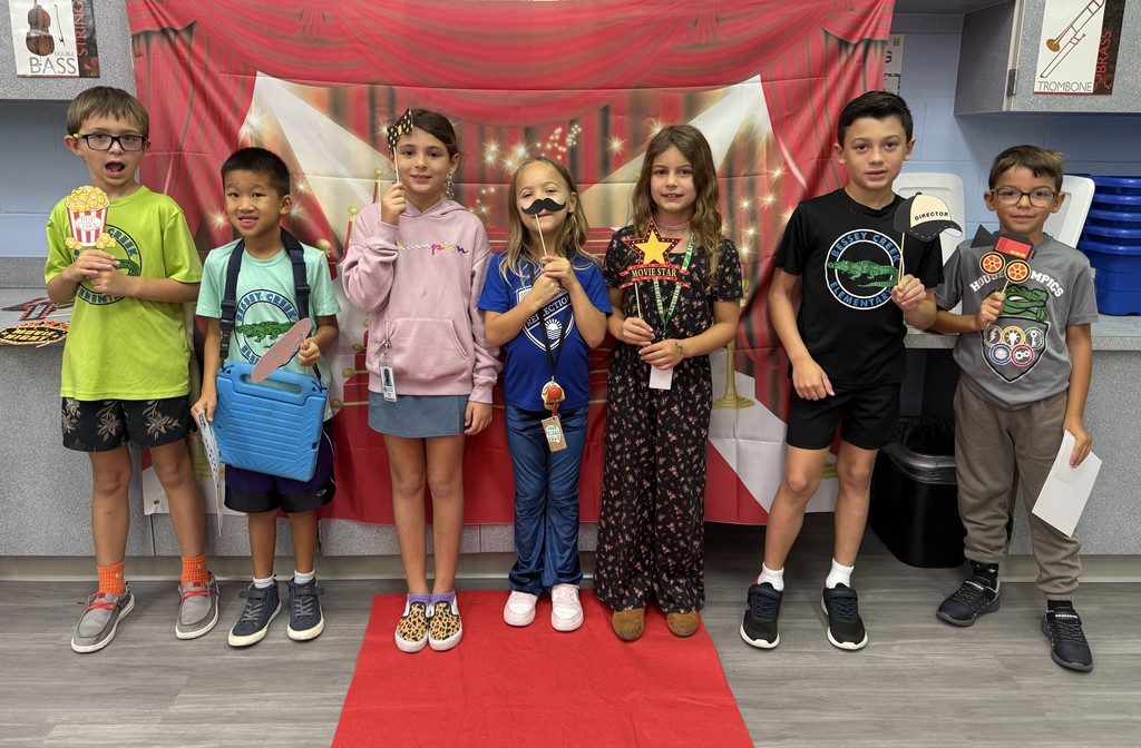 S.T.A.R. Gator Students pose in a room with a red carpet backdrop.