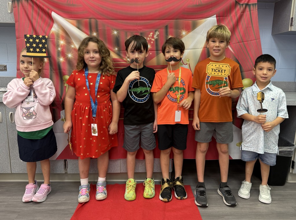 S.T.A.R. Gator Students pose in a room with a red carpet backdrop.