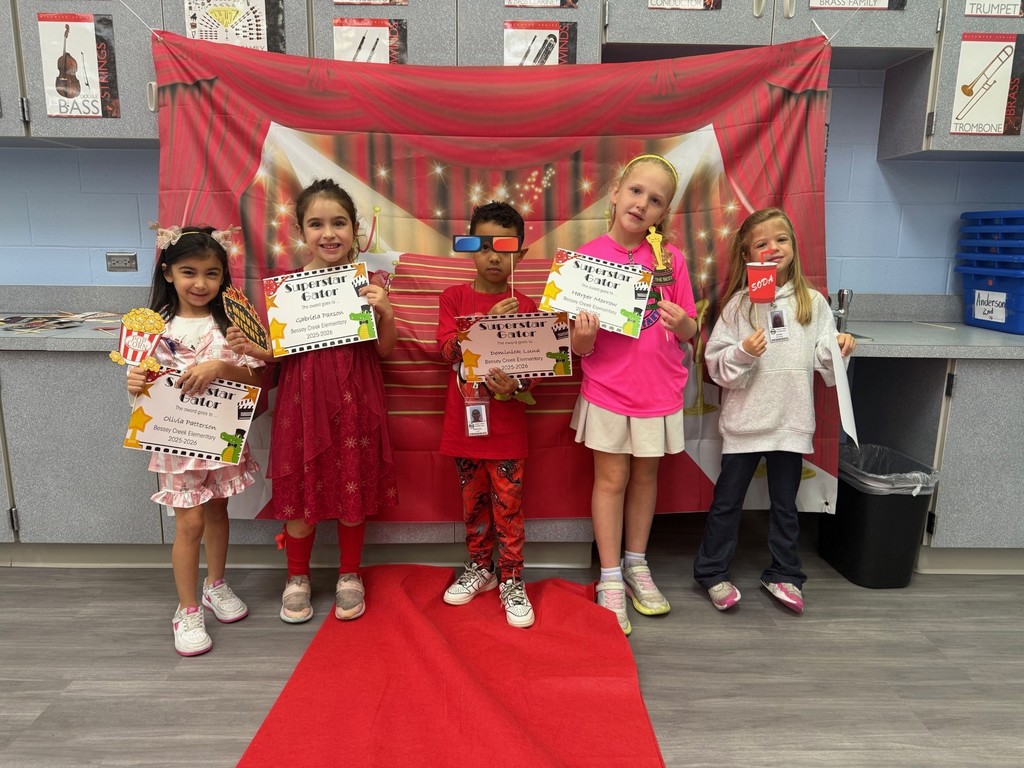 S.T.A.R. Gator Students pose in a room with a red carpet backdrop.