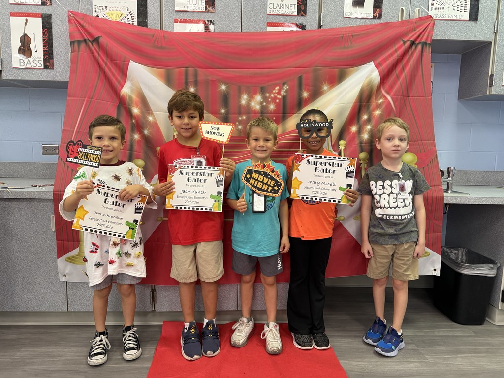 S.T.A.R. Gator Students pose in a room with a red carpet backdrop.