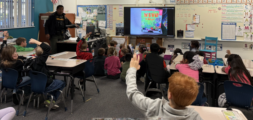 2026 Literacy Week - Ms. Thompson's first grade sharing a book with M.C. Officer