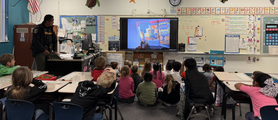 2026 Literacy Week - Ms. Thompson's first grade sharing a book with M.C. Officer 3