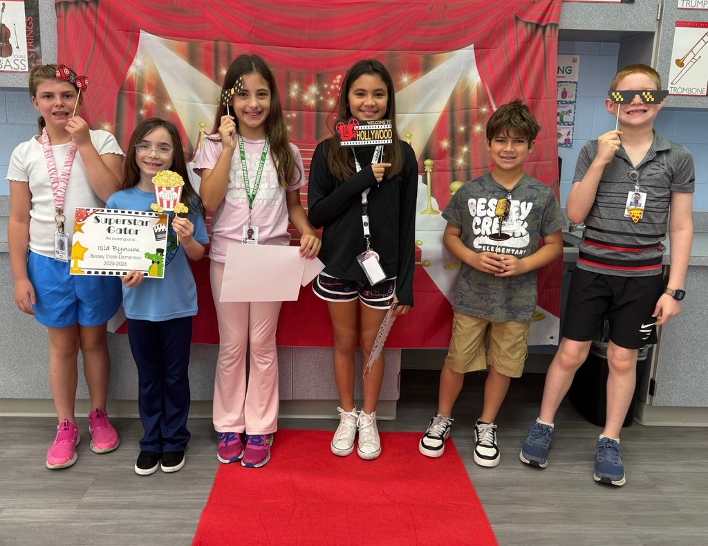 S.T.A.R. Gator Students pose in a room with a red carpet backdrop.