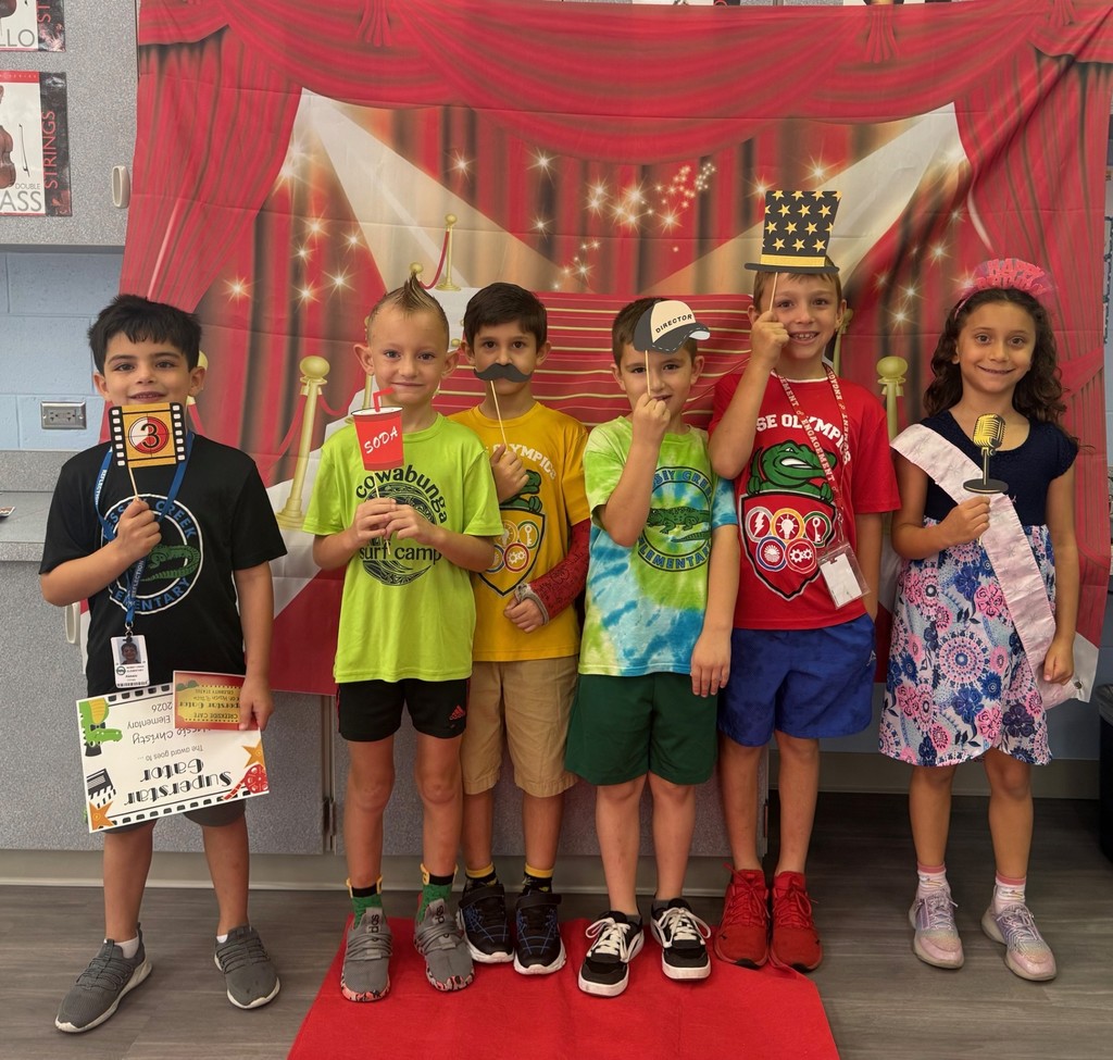 S.T.A.R. Gator Students pose in a room with a red carpet backdrop.