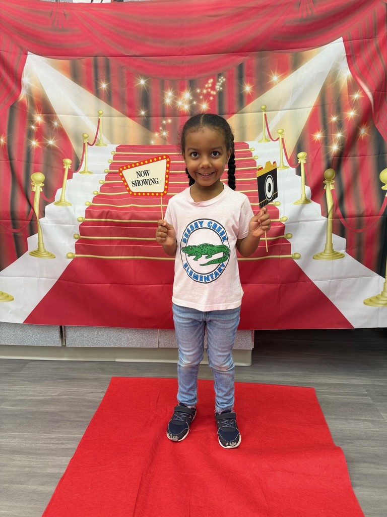 A S.T.A.R. Gator Student poses in a room with a red carpet backdrop.