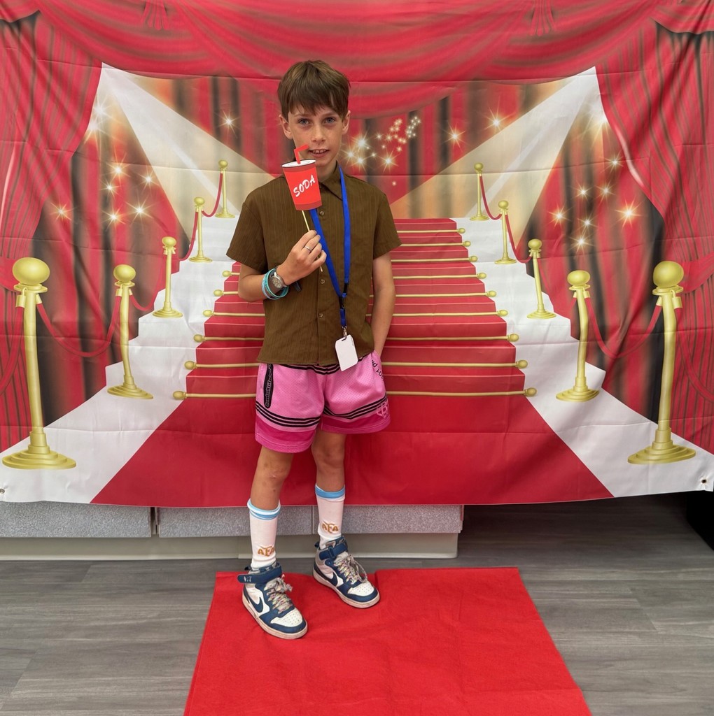 A S.T.A.R. Gator Student poses in a room with a red carpet backdrop.