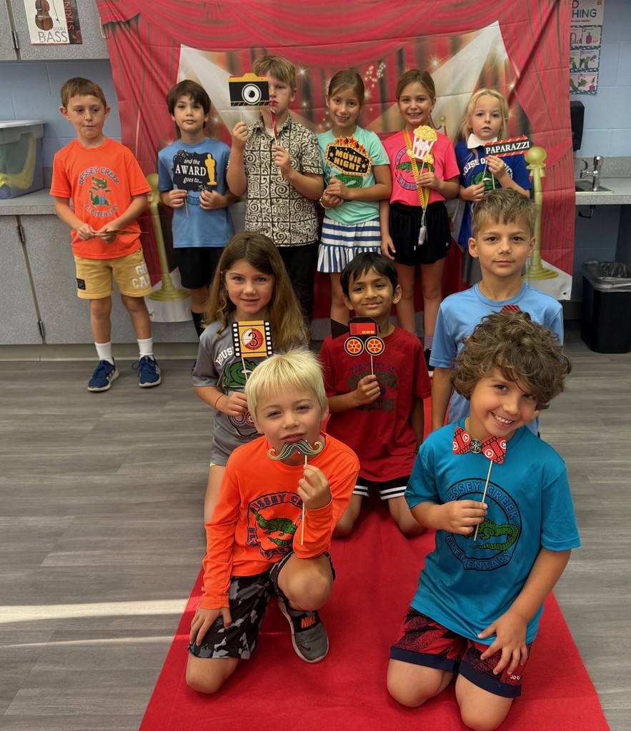 S.T.A.R. Gator Students pose in a room with a red carpet backdrop.