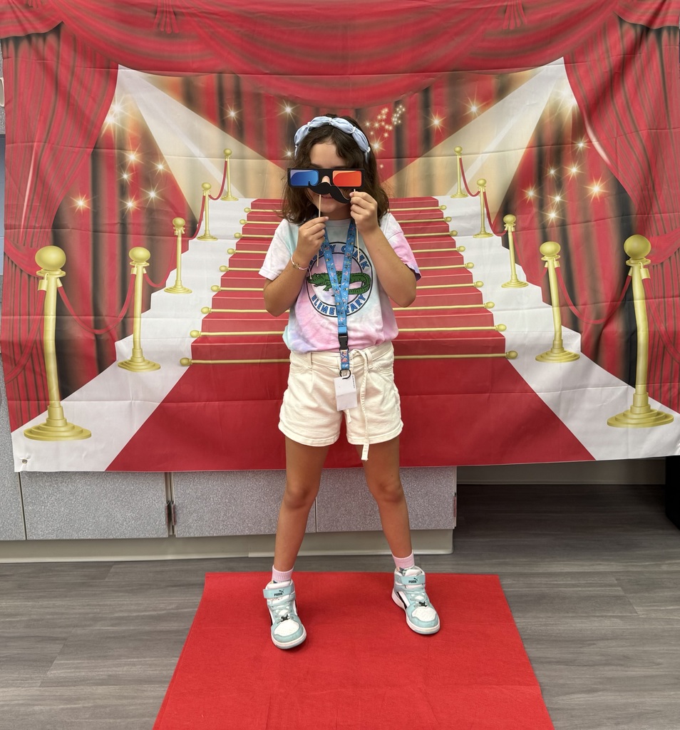 A S.T.A.R. Gator Student poses in a room with a red carpet backdrop.