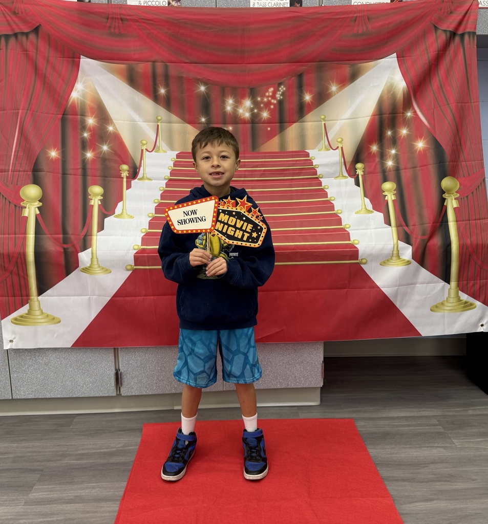 A S.T.A.R. Gator Student poses in a room with a red carpet backdrop.
