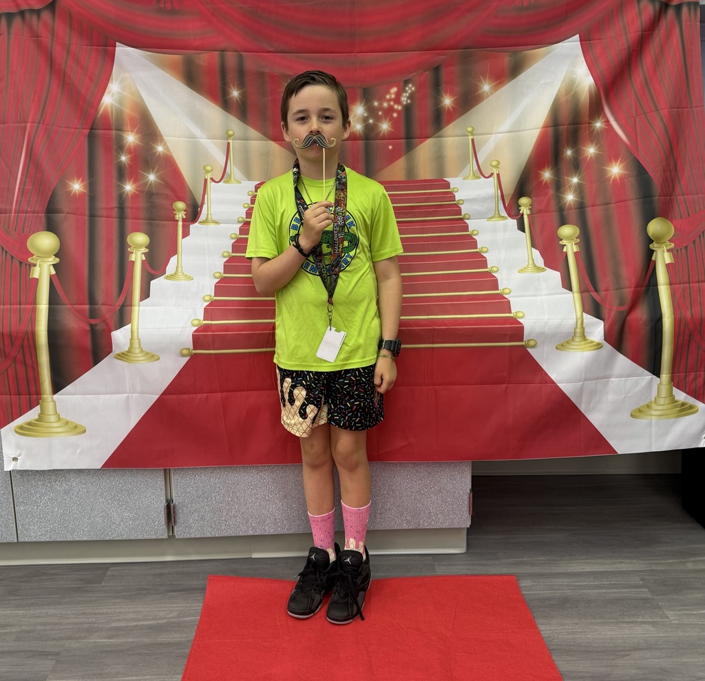 A S.T.A.R. Gator Student poses in a room with a red carpet backdrop.