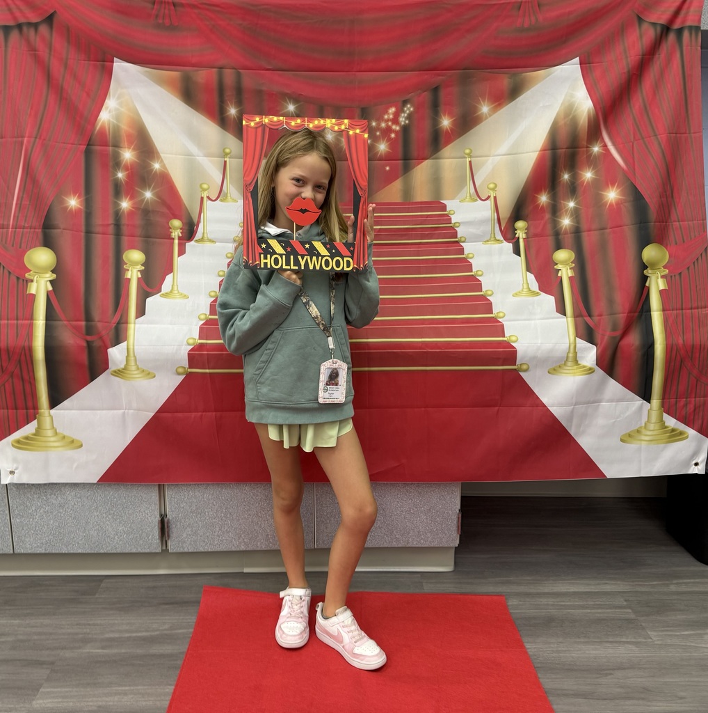 A S.T.A.R. Gator Student poses in a room with a red carpet backdrop.