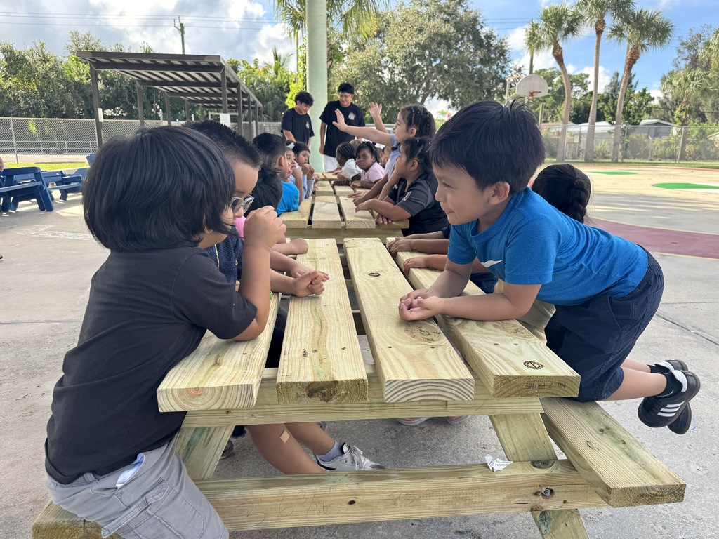 Port Salerno Learning center students smiling on new picnic bench made by SFHS construction students