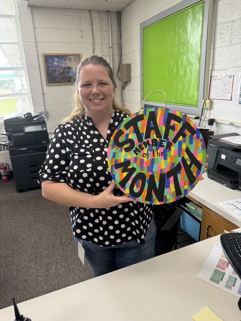 Mrs. Thompson proudly holds her award, which reads, "Staff Member of the Month"
