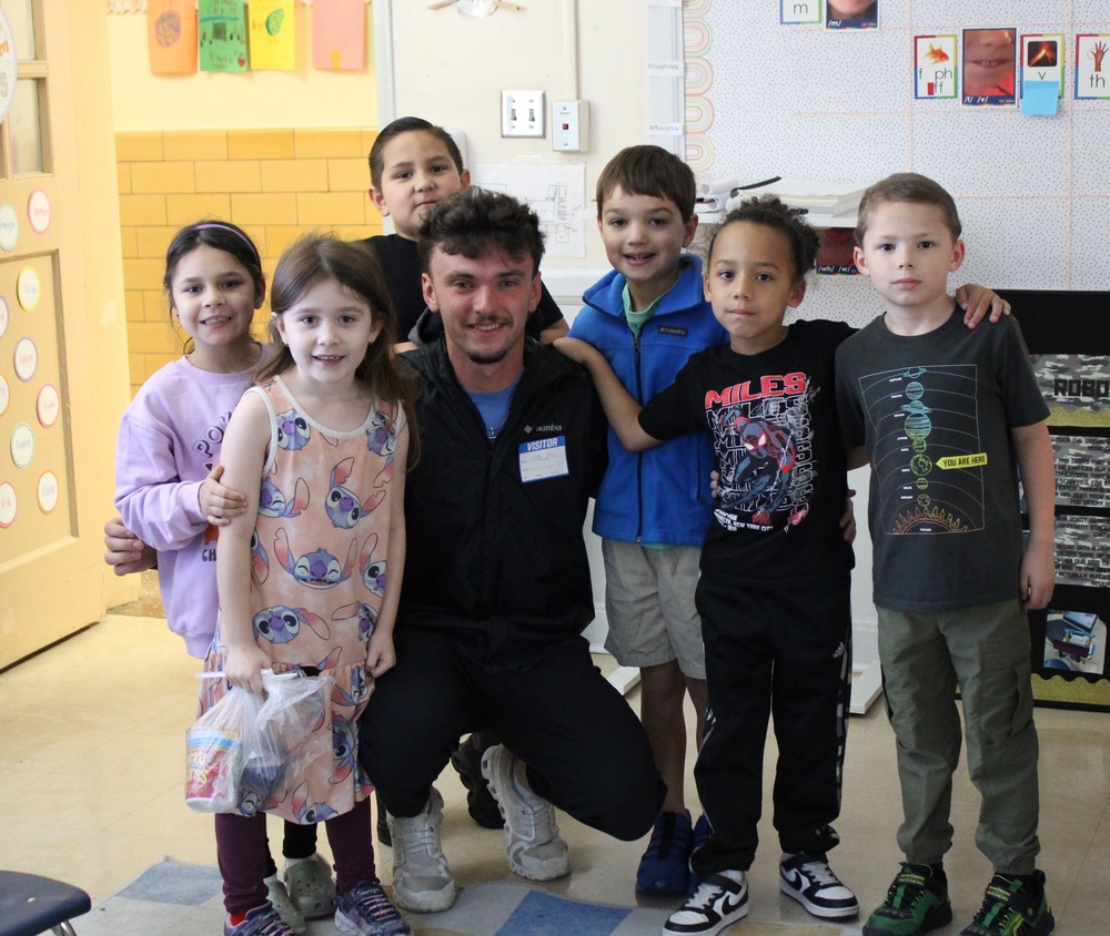 A P&HCC baseball player poses for a photo with a group of elementary students in their classroom