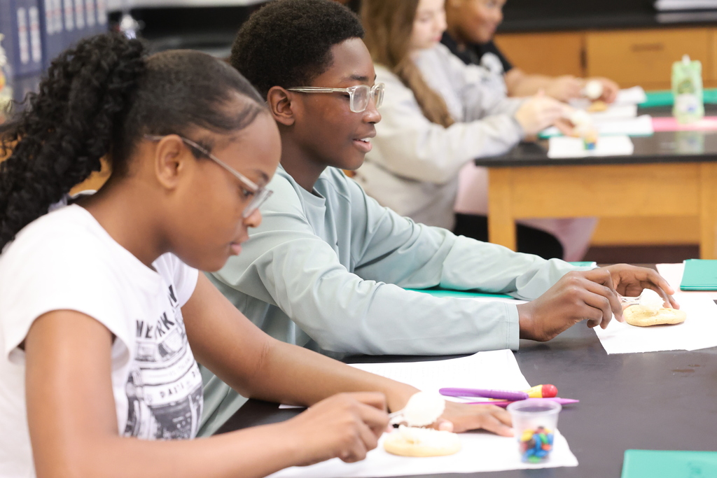 Eighth grade students use cookies, icing, and colorful M&M’s to build edible models of lithium atoms during a hands-on science lesson.