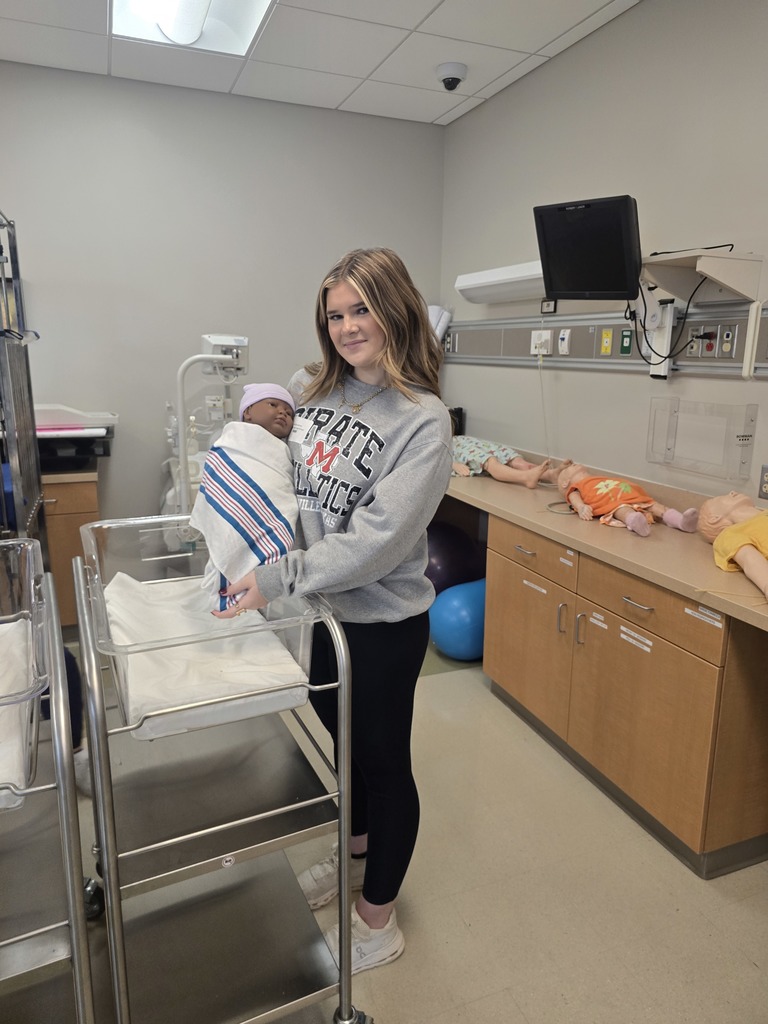 Jaycie Latham holding a newborn mannequin that she just swaddled.