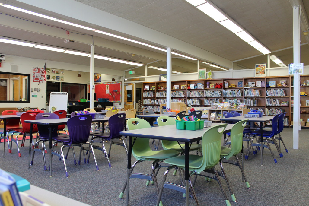 Colorful chairs sit around tables in a school library