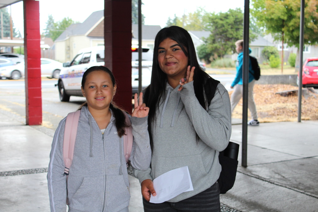 Two kids give peace signs and smile