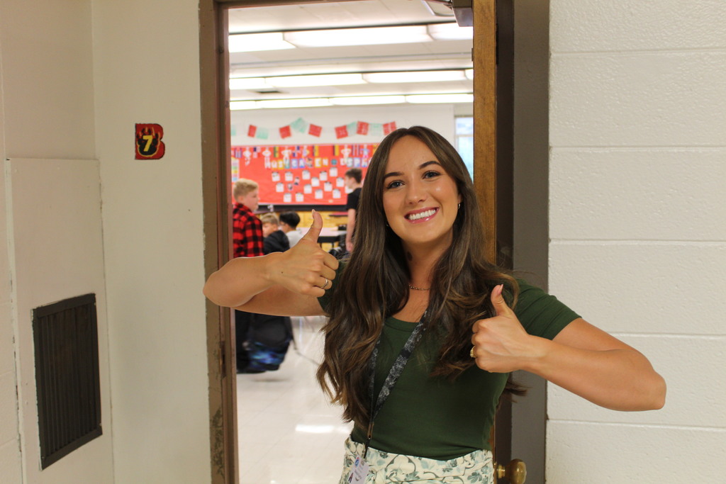 A teacher smiles and gives a thumbs up
