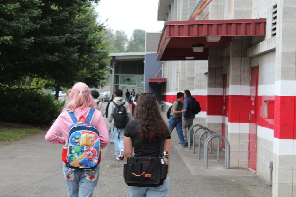Students are walking next to a red striped wall