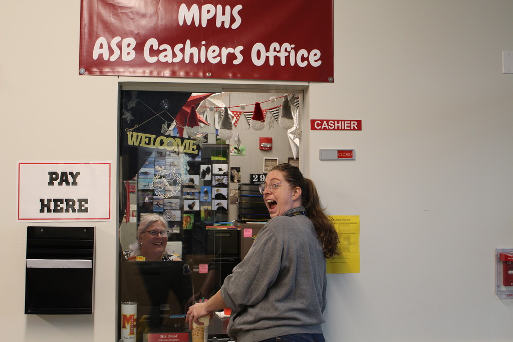 Two staff members smile widely under a sign that says "MPHS ASB Cashiers Office"