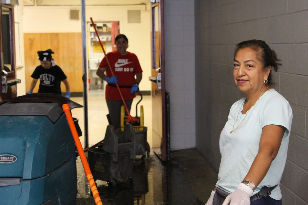 Custodial staff pose for the camera in the middle of their work
