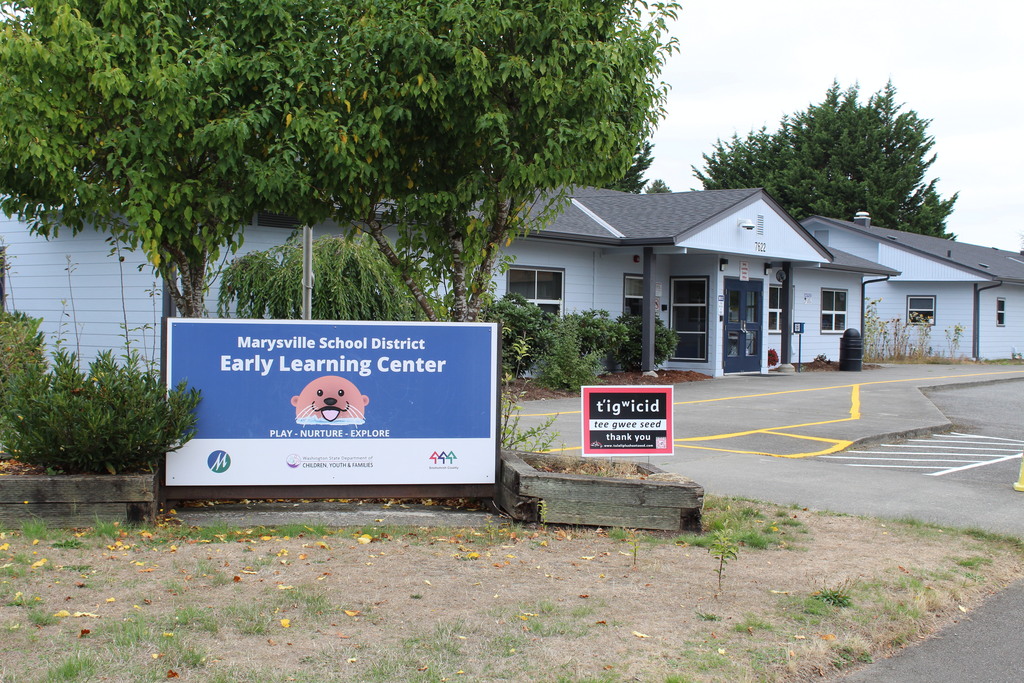 The MSD Early Learning Center is pictured. The building is blue and there is a sign out front with the building name, and another sign that is smaller and red and black that shows the Lushootseed word for "thank you"