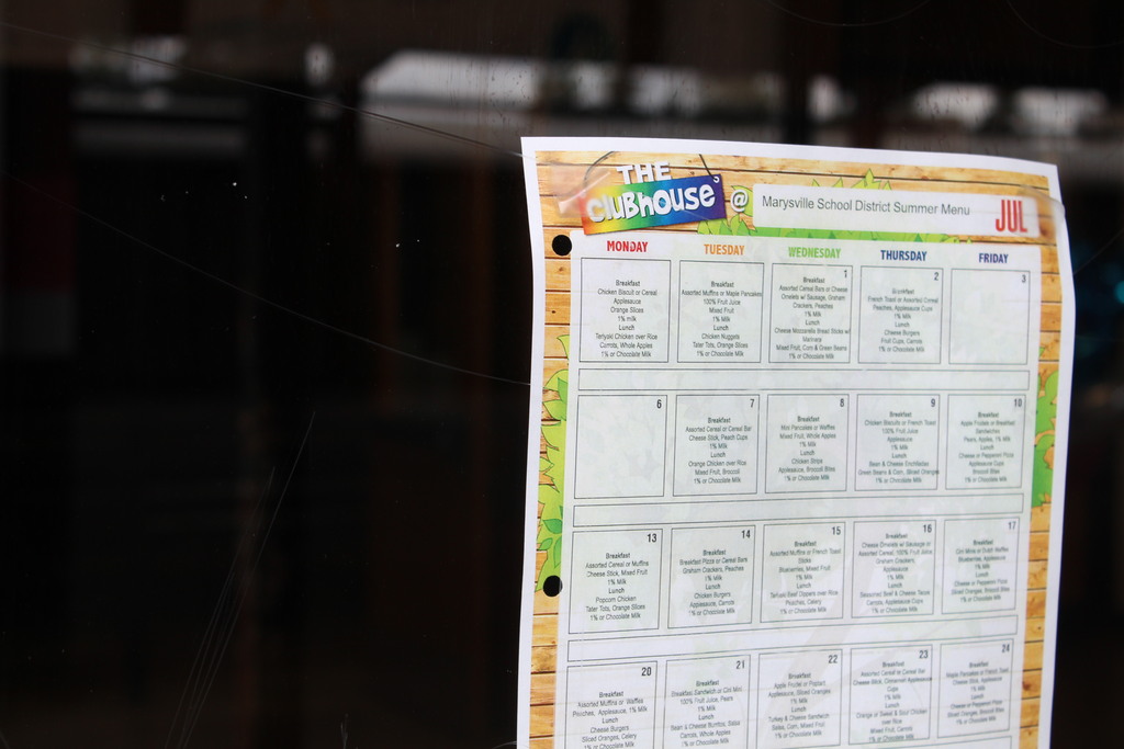 The summer meals menu is seen in a window with a dark background behind