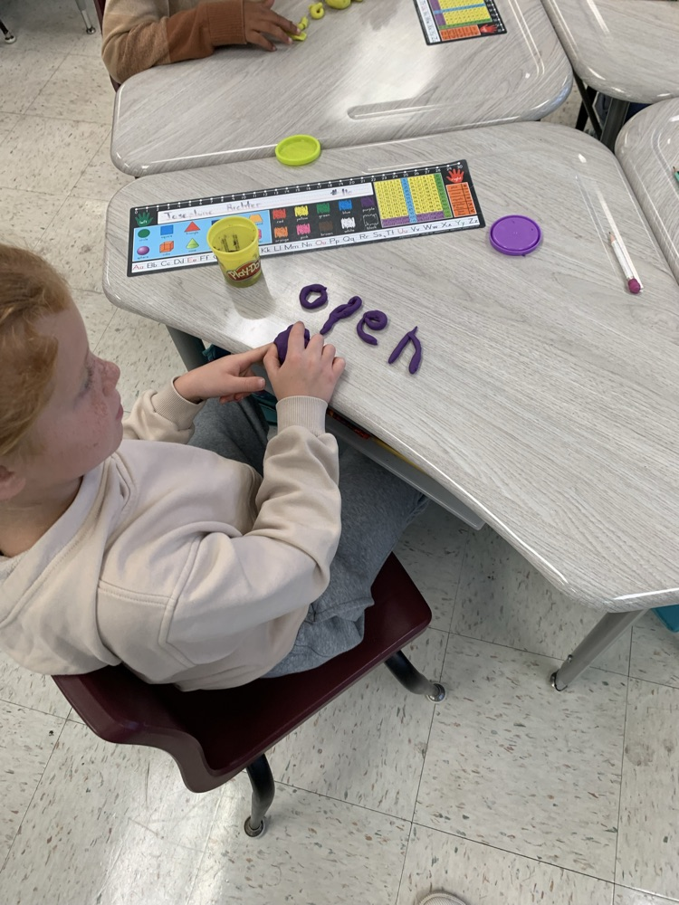 kid spelling word with playdoh