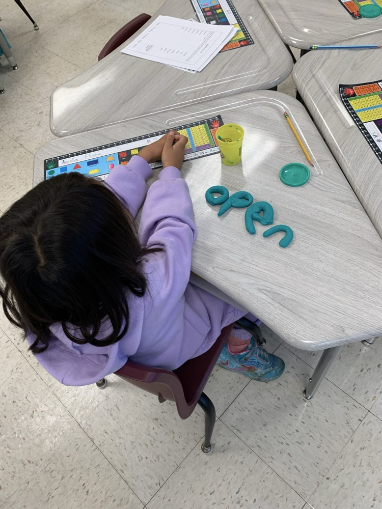 kid spelling word with playdoh