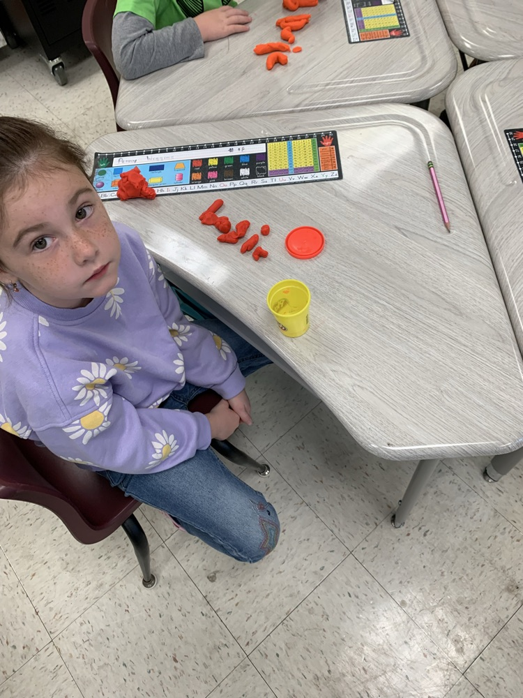 kid spelling word with playdoh