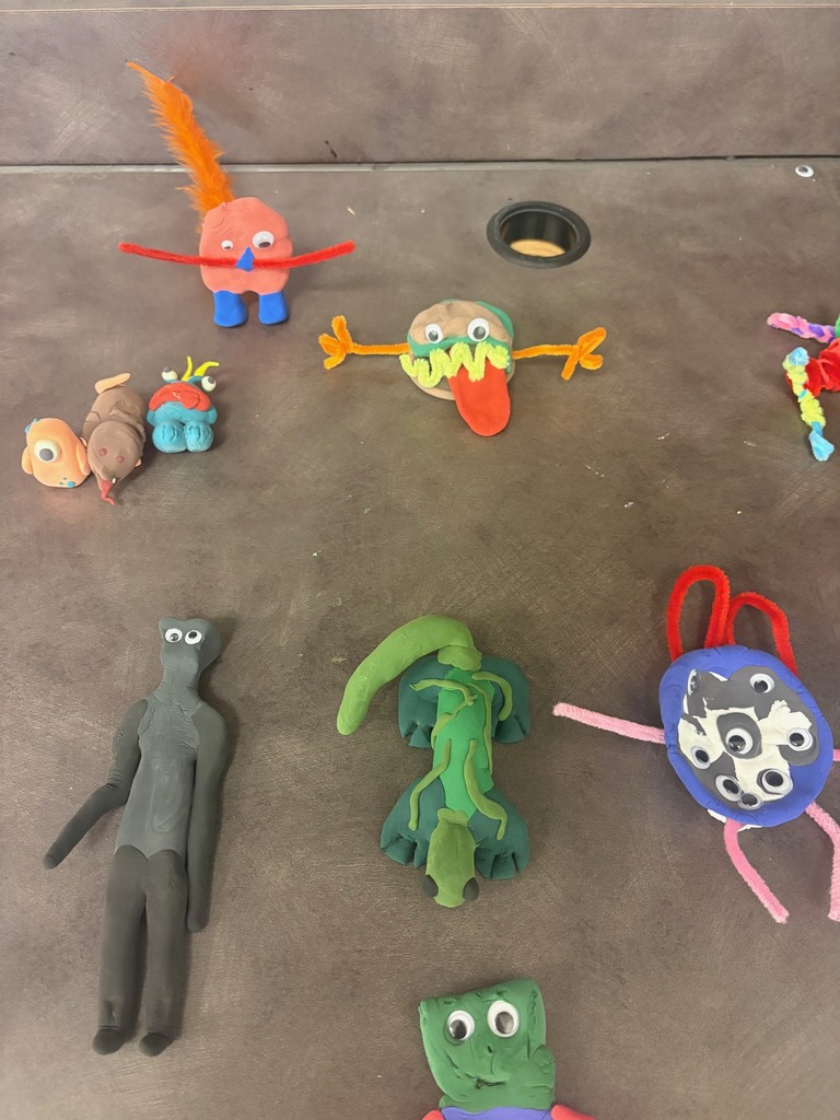 Picture is of clay monsters created by students with bold colors and creative designs to fit the theme of the story.