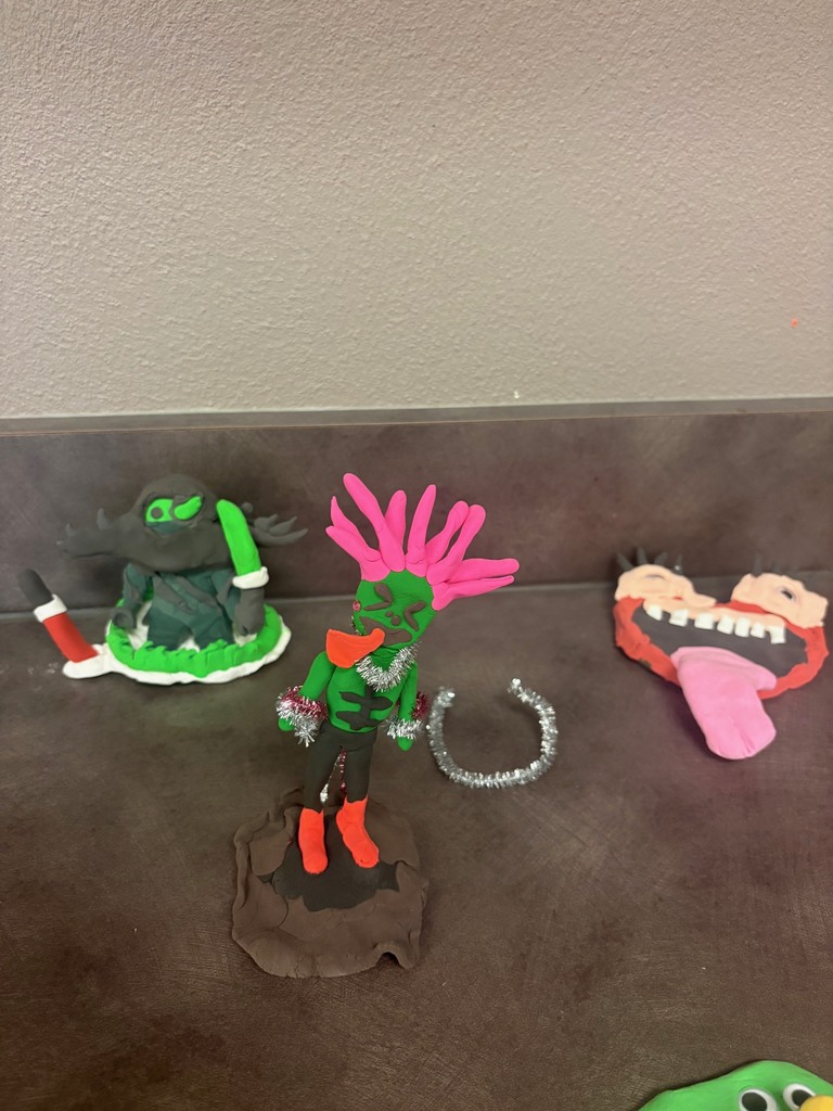 Picture is of clay monsters created by students with bold colors and creative designs to fit the theme of the story.