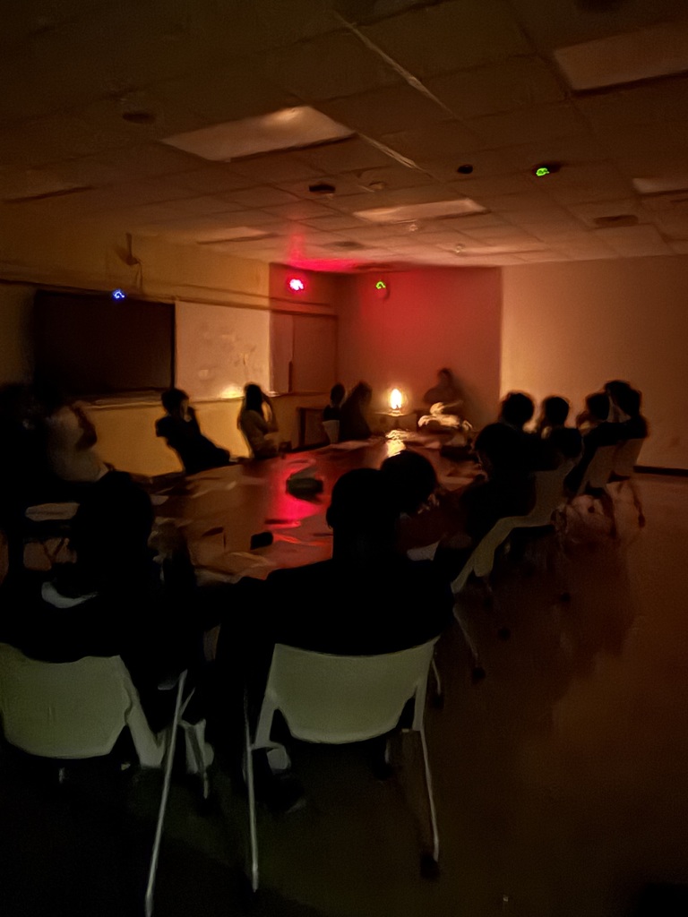 Students viewing illuminated gas through diffraction gratings in a dark room.