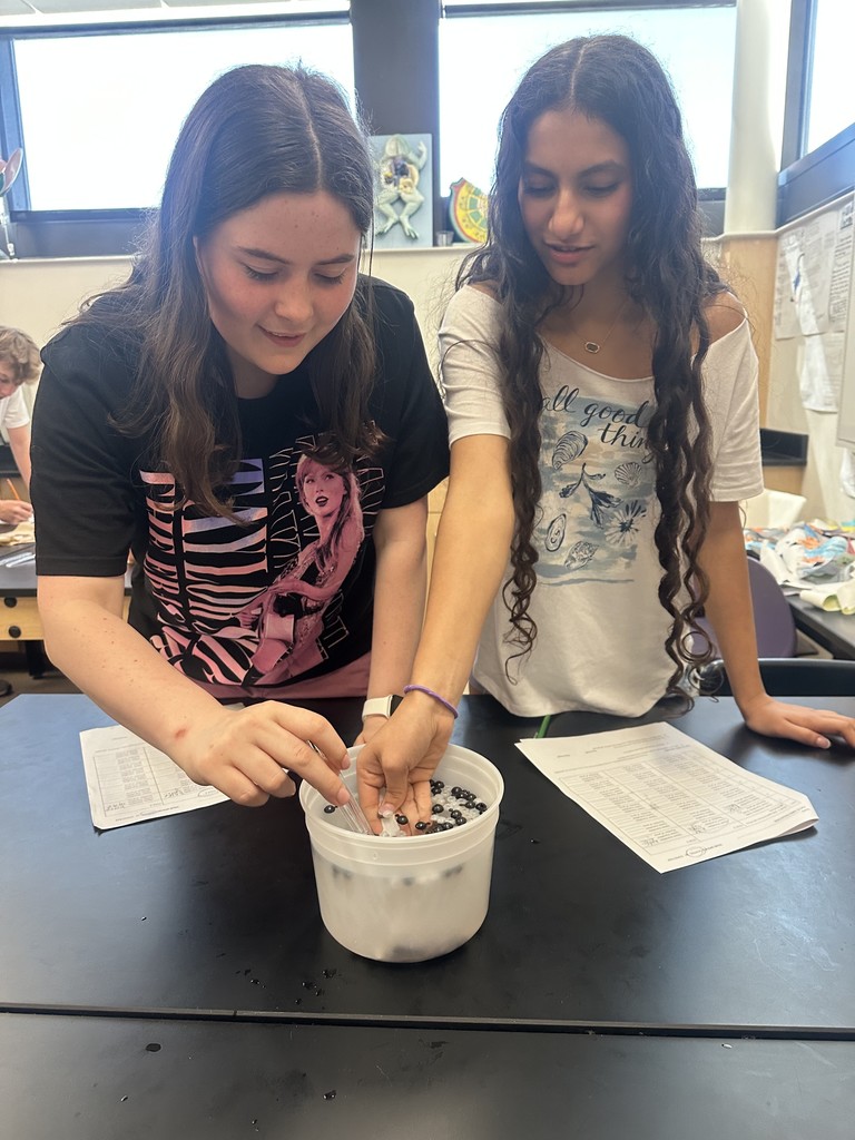 Students diving for beads using spoons.