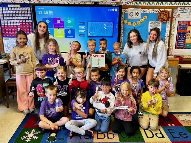 Group picture of MHS students with some elementary students showing off their spoons.