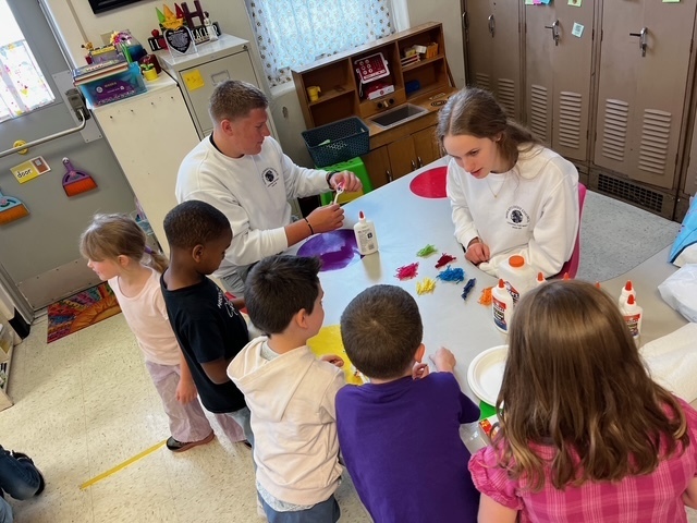 Two MHS students helping elementary students pick out yarn for their craft.