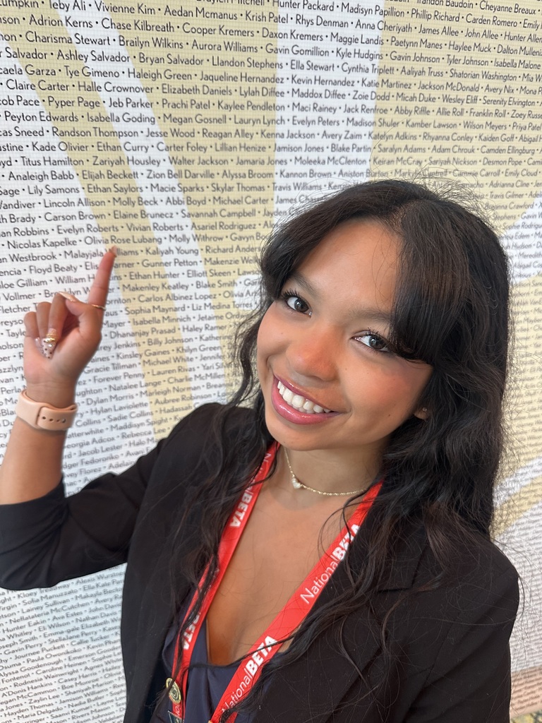 Olivia Lubang pointing to her name on the National Beta Convention wall of competitors!