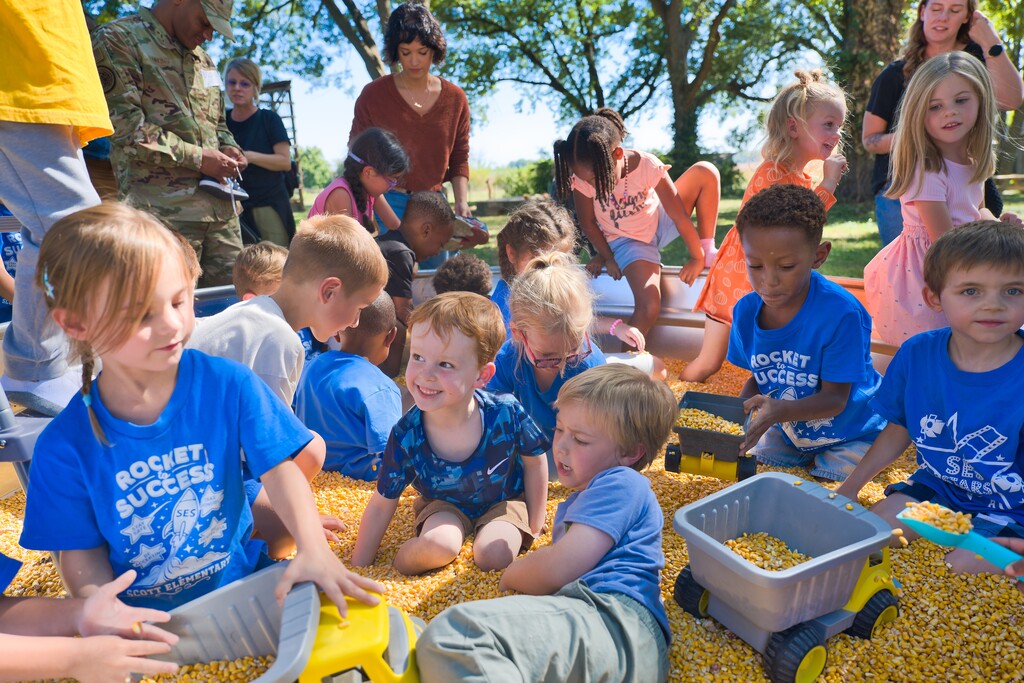 Kindergartners playing in a tub of corn.