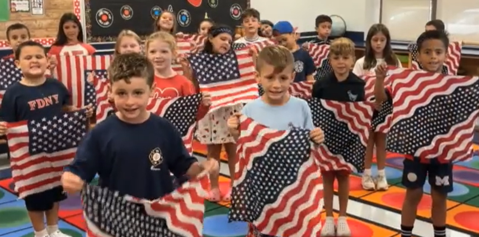 Students wave flags during singing of national anthem